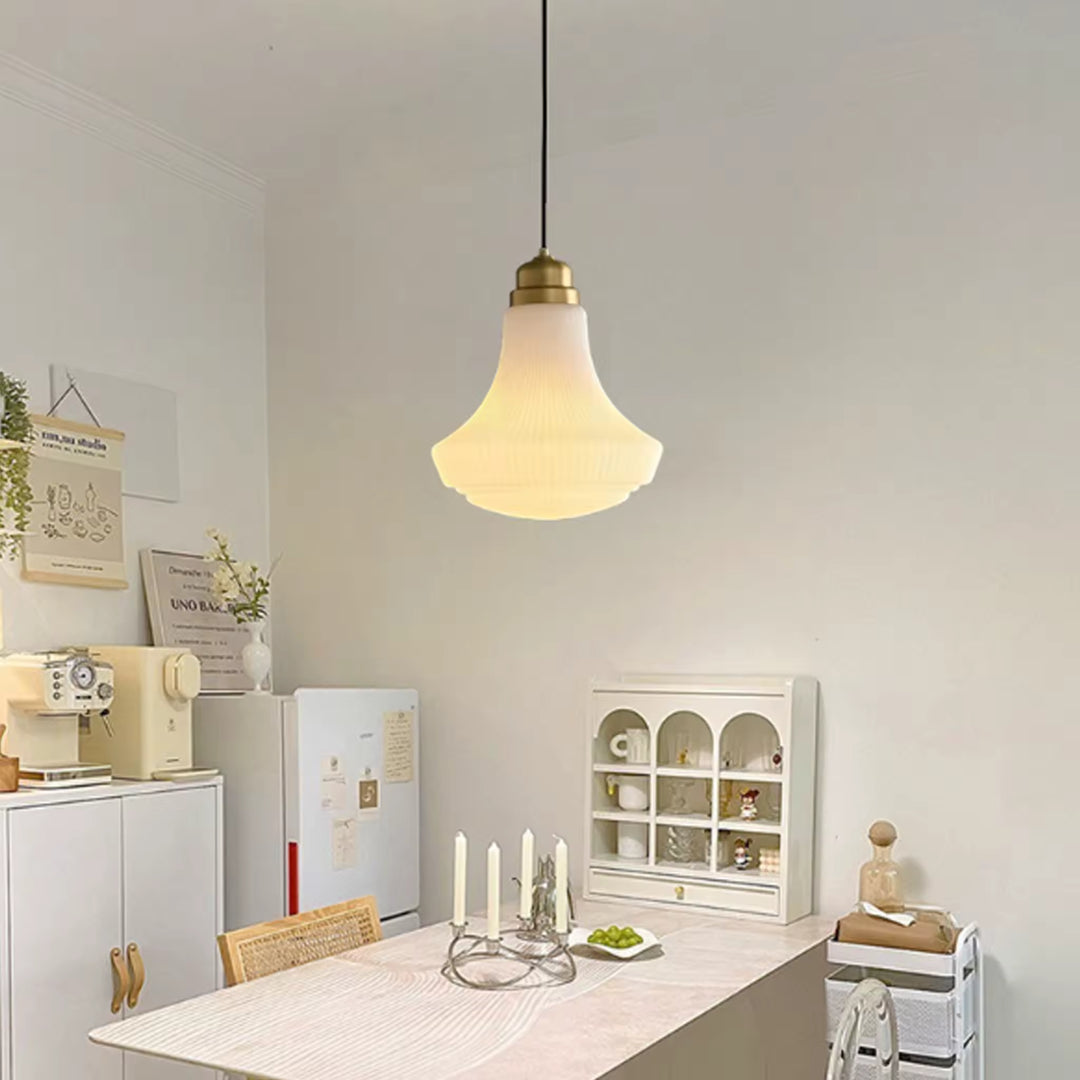 Suspension en opaline nervurée et finition laiton, diffusant une lumière douce au-dessus d’une salle à manger rétro