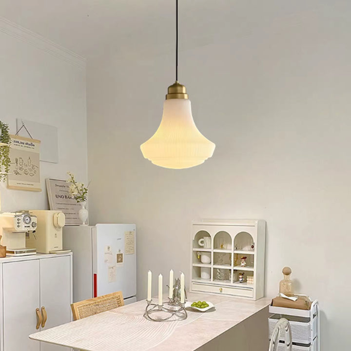 Suspension en opaline nervurée et finition laiton, diffusant une lumière douce au-dessus d’une salle à manger rétro