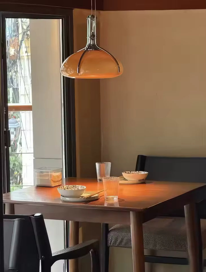Luminaire orange à dôme chromé suspendu au-dessus d’une table, dans une ambiance rétro chic aux accents Space Age