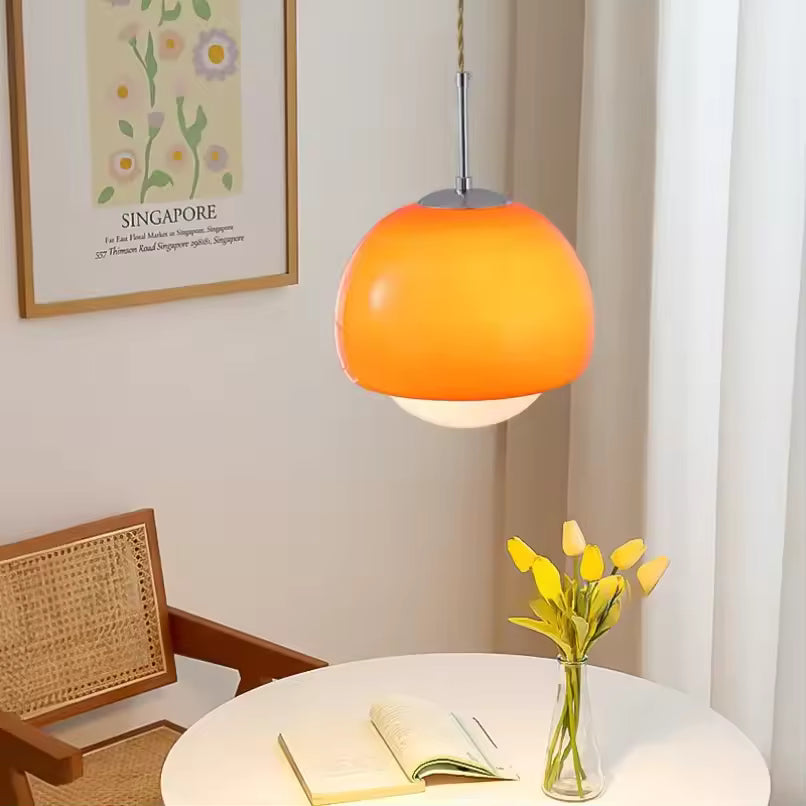 Suspension orange à globe opalin au style pop des années 70, installée au-dessus d’une table ronde