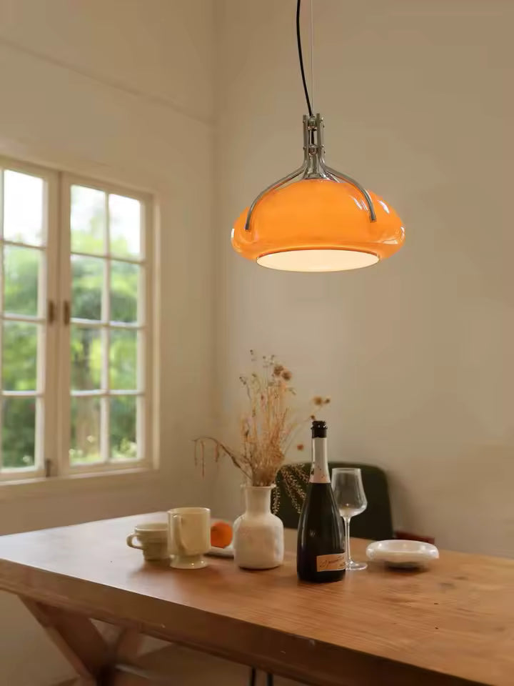 Suspension orange à dôme chromé éclairant une table en bois, dans un intérieur vintage aux accents Space Age