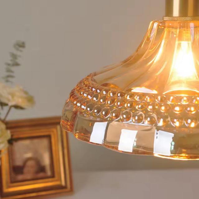 Zoom sur la suspension orange vintage en verre, révélant des détails raffinés et une lumière rétro chaleureuse.