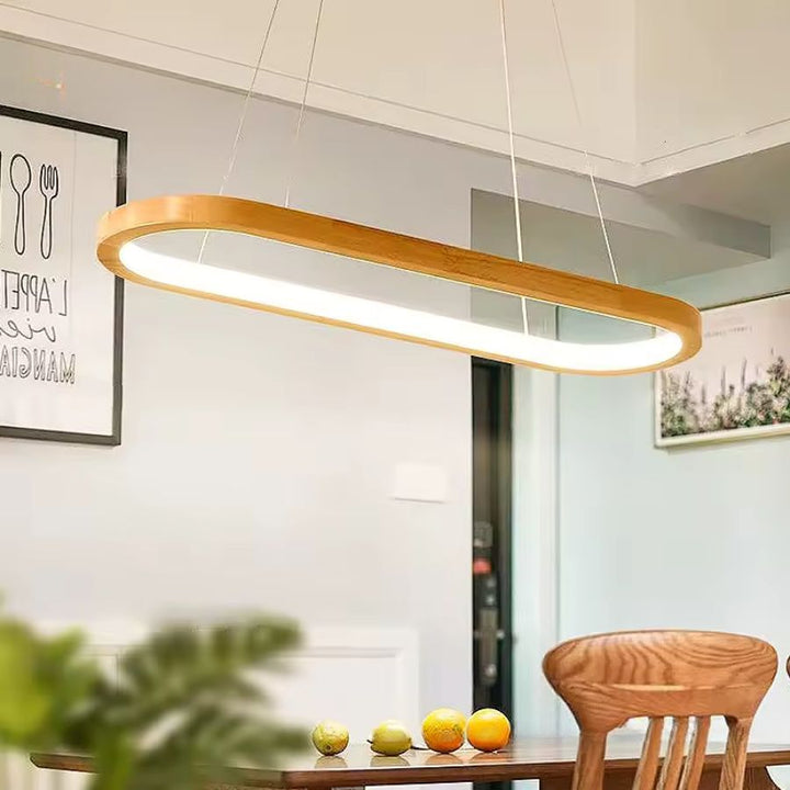 Au-dessus de la table, cette suspension ovale en bois diffuse une lumière LED douce dans un décor moderne et naturel