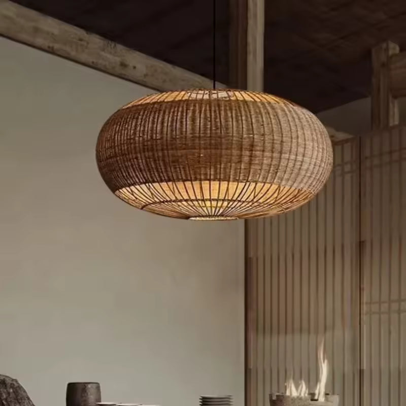 Une suspension ovale en rotin tressé aux lignes ajourées éclaire un intérieur rustique au style wabi-sabi et naturel.