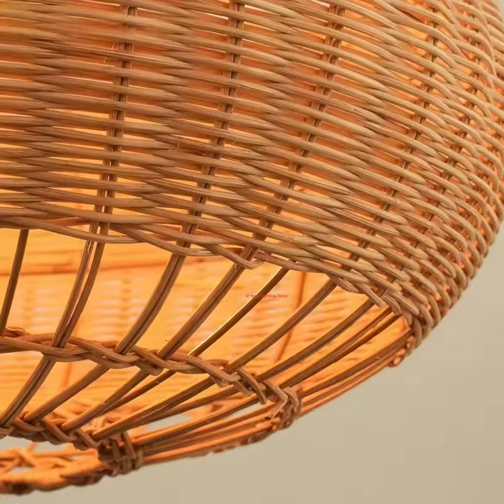 Gros plan sur le tressage serré et les fibres de rotin ajourées d'une suspension ovale au style naturel et bohème.