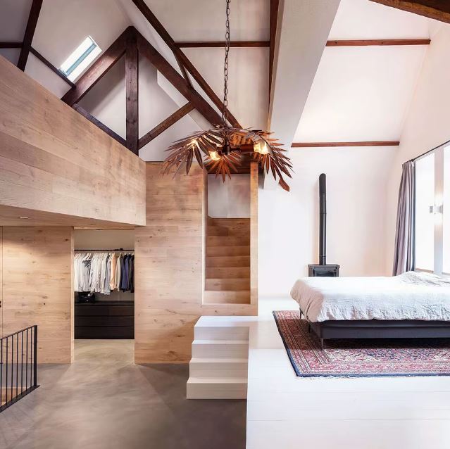 Suspension palmier en métal cuivré installée dans une chambre avec poutres apparentes, pour une ambiance chaleureuse et naturelle.