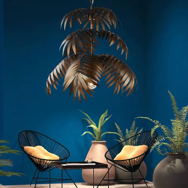 Suspension palmier suspendue au-dessus d’un salon tropical moderne avec fauteuils noirs et murs bleu profond.