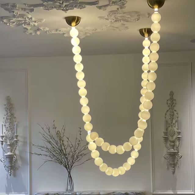 Suspension perle élégante avec un design contemporain, mise en valeur dans un salon raffiné aux moulures décoratives.