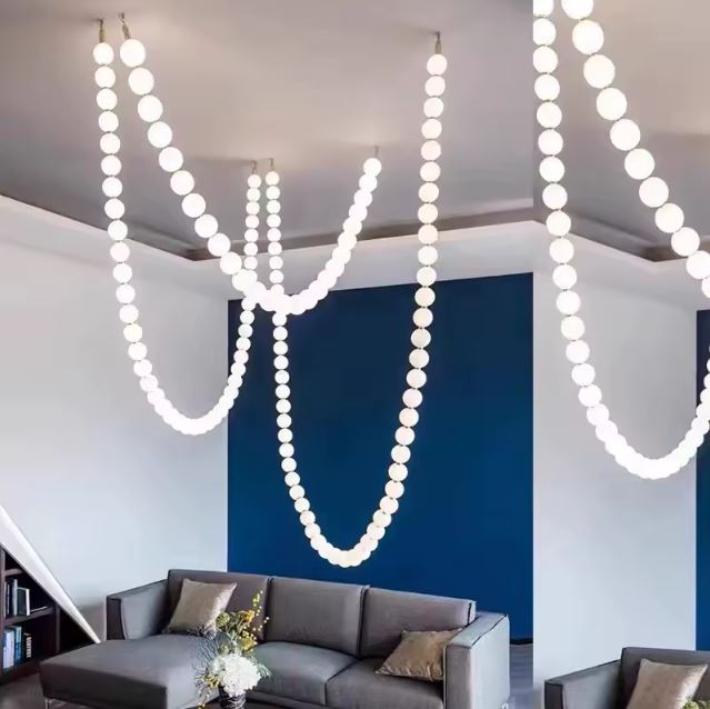 Suspension perle moderne suspendue au plafond d'un salon élégant avec des murs bleus et un canapé confortable.