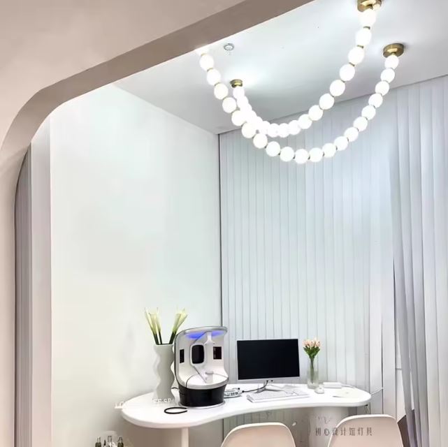 Suspension perle élégante éclairant un espace de travail minimaliste, idéale pour une ambiance raffinée et lumineuse.