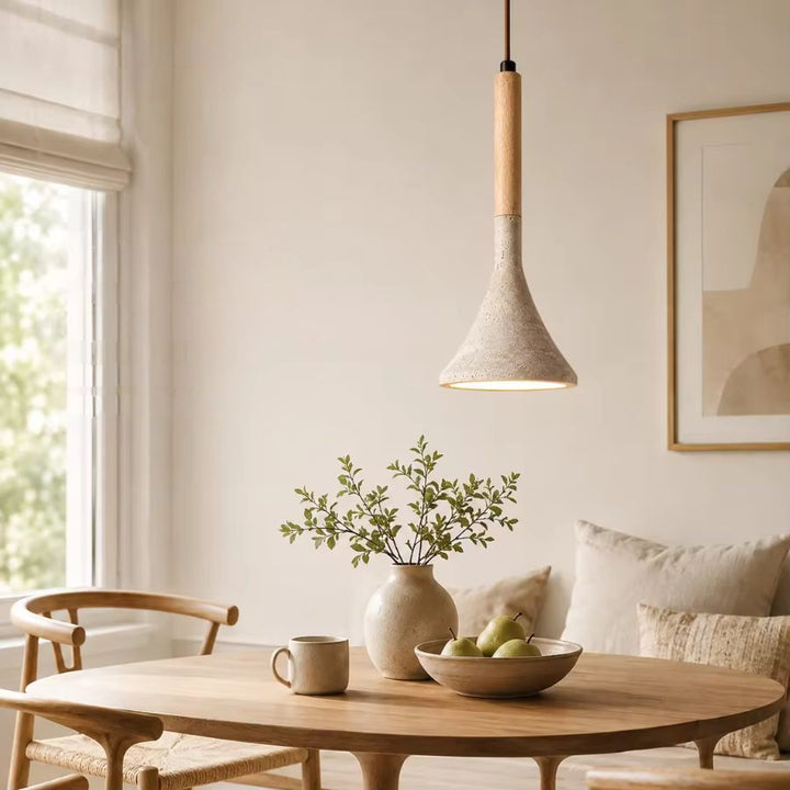 Au-dessus d’une table en bois clair, ce luminaire en pierre et bois s’intègre dans une salle à manger scandinave apaisante