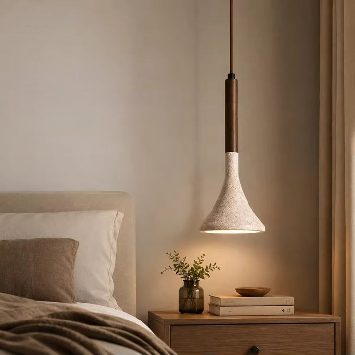 Au-dessus du chevet, ce luminaire suspendu en pierre claire et bois foncé crée une ambiance douce dans une chambre chaleureuse