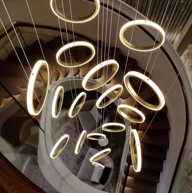 Vue plongeante d'une suspension plafond cathédrale LED design avec anneaux dorés, parfaite pour escalier en colimaçon.