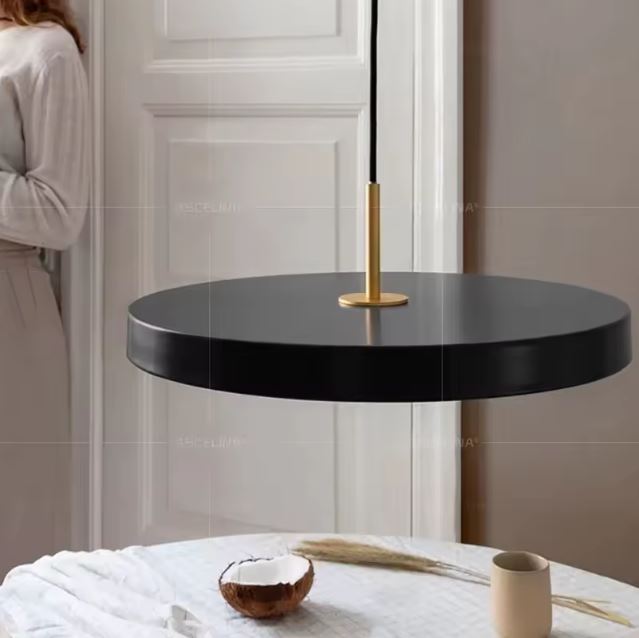 Suspension plate noire avec des finitions dorées suspendue au-dessus d'une table décorée dans un intérieur raffiné et élégant.