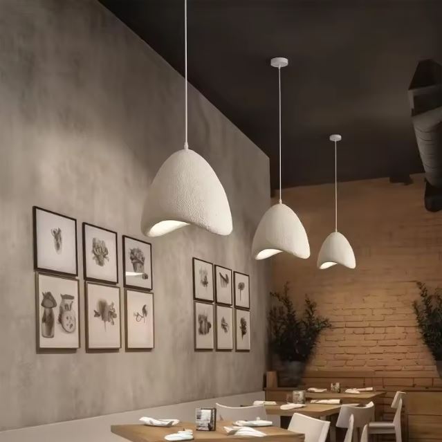 Trio de suspensions en plâtre blanc Style D éclairant un restaurant moderne et chaleureux avec un design élégant.