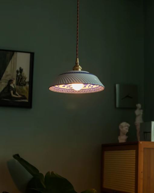 Suspension en porcelaine blanche nervurée à frise florale bleue, diffusant une lumière douce, idéale pour un décor romantique ou campagne chic.
