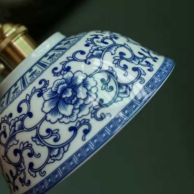 Suspension en porcelaine blanche aux tracés bleus délicatement ouvragés, détail floral mettant en valeur son style artisanal raffiné et vintage.