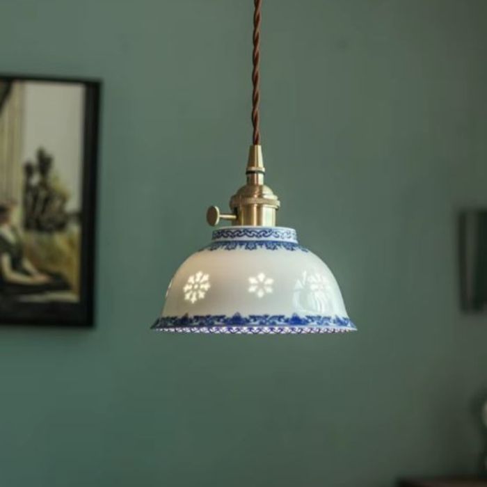 Suspension en porcelaine fine aux arabesques bleues ajourées, diffusant une lumière douce dans un style vintage élégant et campagne chic.