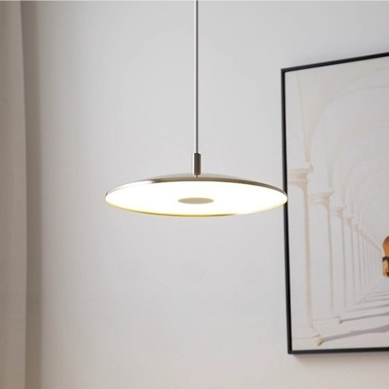 Vue rapprochée d'une suspension design ronde en métal diffusant une lumière chaleureuse dans un salon.