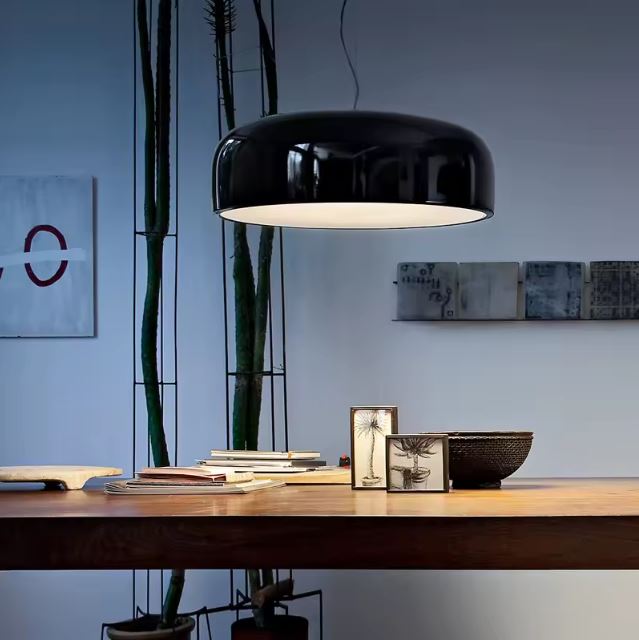 Suspension ronde noire suspendue au-dessus d'une grande table en bois, parfaite pour une déco naturelle mêlant modernité et chaleur.