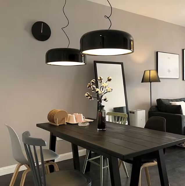Suspension ronde noire en duo au-dessus d’une table, idéale pour un intérieur contemporain mêlant design épuré et ambiance cosy.