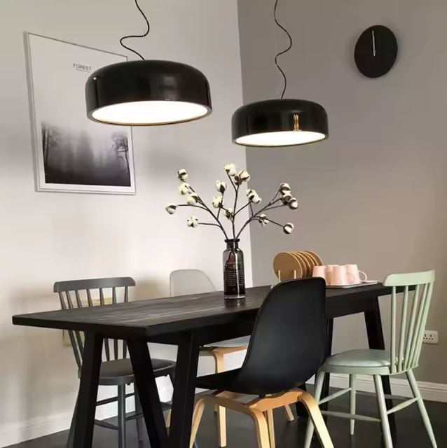 Duo de suspensions rondes noires dans une salle à manger aux chaises dépareillées, parfaites pour une déco scandinave tendance.