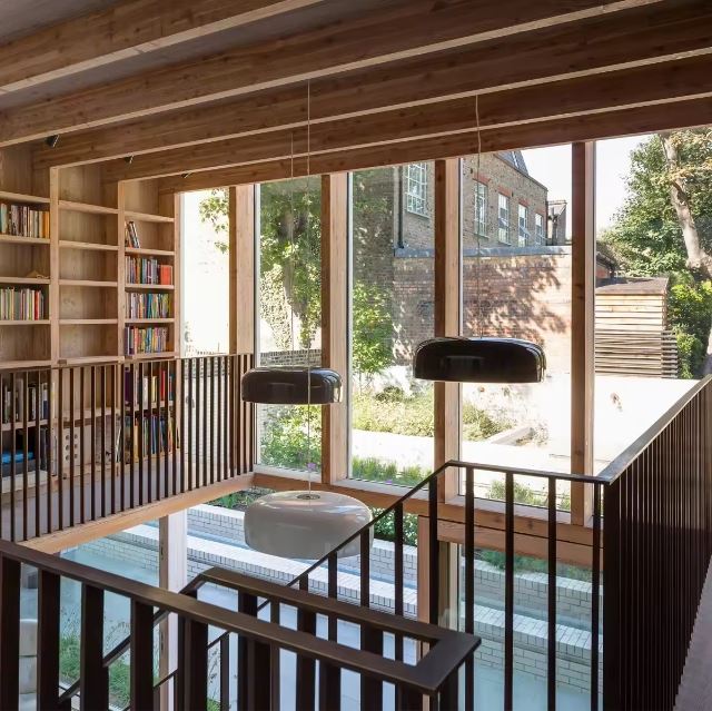 Suspensions rondes noires dans un espace mezzanine en bois avec vue sur jardin, parfaites pour une déco naturelle et contemporaine.