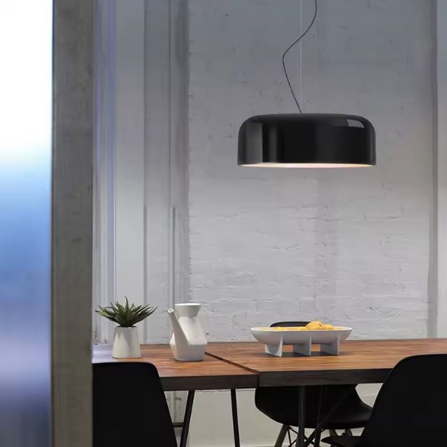 Suspension ronde noire moderne suspendue au-dessus d’une table en bois, idéale pour une salle à manger au style sobre et raffiné.