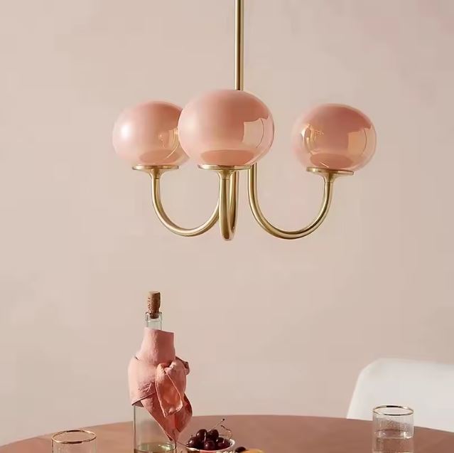 Suspension rose à trois boules en verre sur structure laiton, idéale pour une ambiance romantique et élégante en salle à manger.