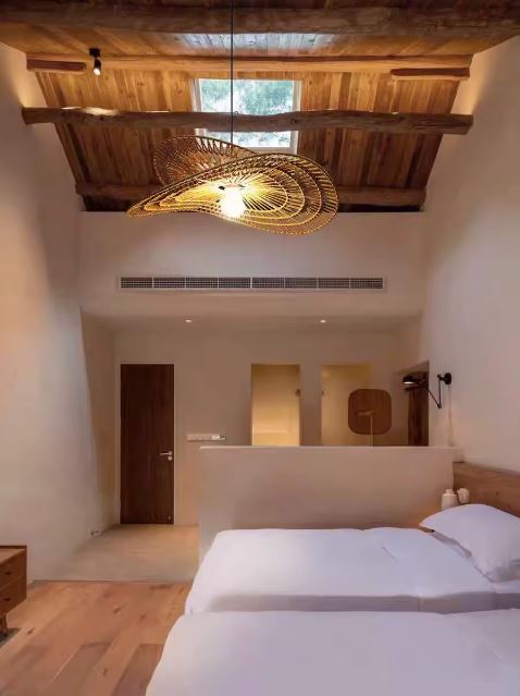 Suspension en rotin bohème et naturel, luminaire chaleureux installé dans une chambre au plafond en bois massif.