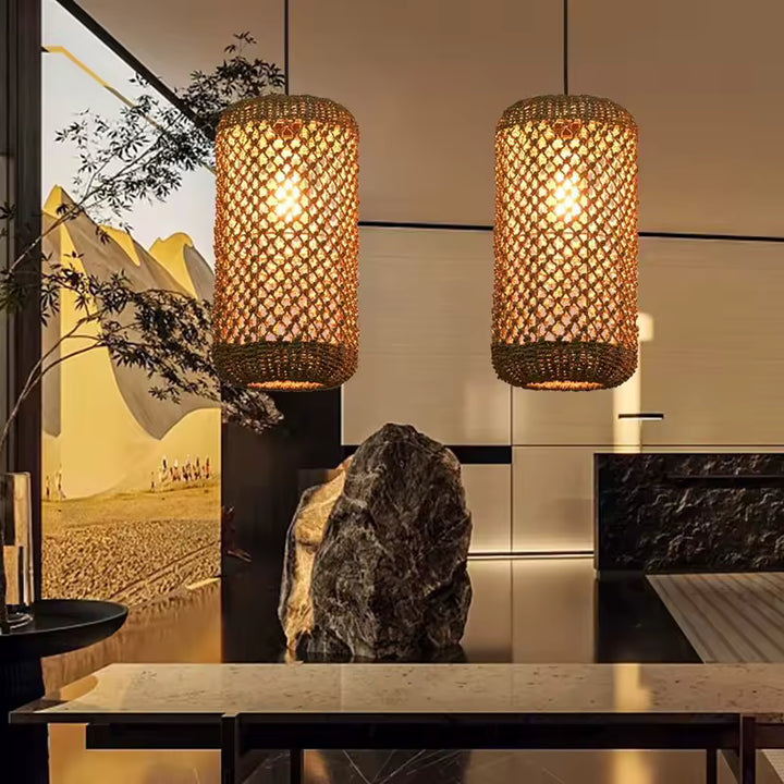 Deux suspensions cylindriques en rotin à mailles ajourées diffusent une lumière chaude dans un intérieur zen et naturel.