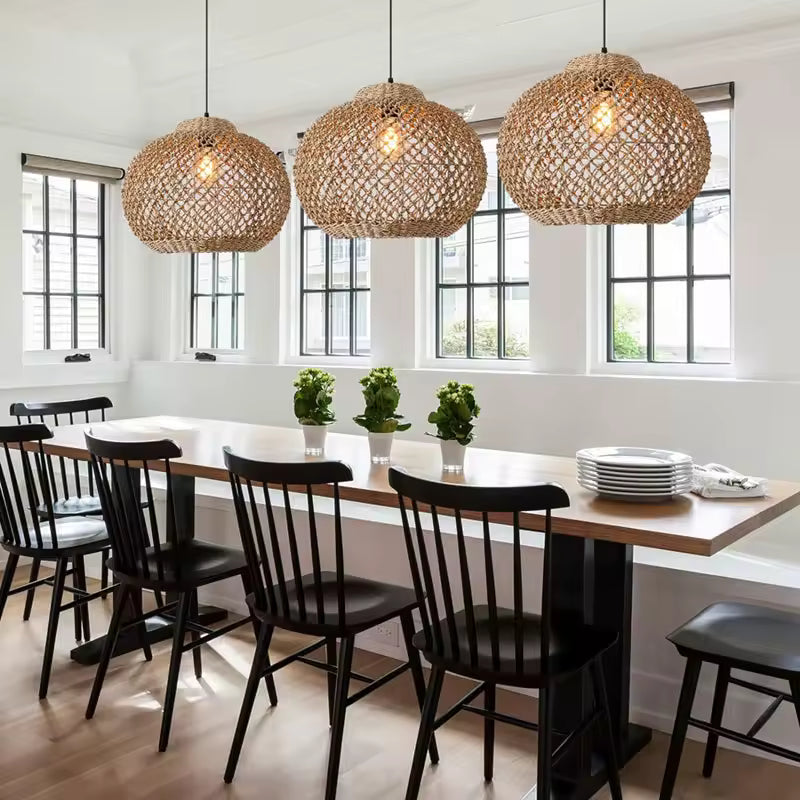 Trois suspensions en rotin tressé à mailles ajourées et forme arrondie surplombent une table dans une salle à manger scandinave.