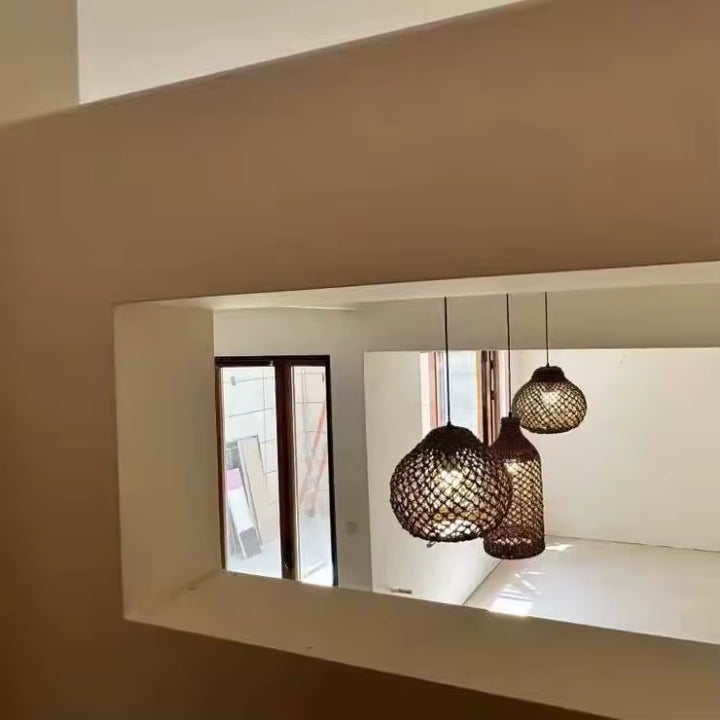 Vue en hauteur de trois suspensions en rotin à mailles ajourées, aux formes variées, dans un intérieur contemporain naturel.