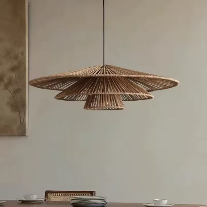 Un lustre en rotin à trois abat-jour coniques ajourés surplombe une table à manger, dans un esprit bohème épuré.