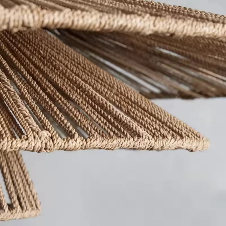 Gros plan sur le tressage ajouré des trois abat-jour en rotin d'une suspension artisanale au style bohème naturel.