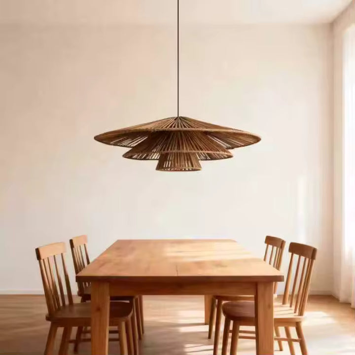 Une suspension en rotin à trois abat-jour étagés surplombe une table en bois clair dans une salle à manger scandinave.