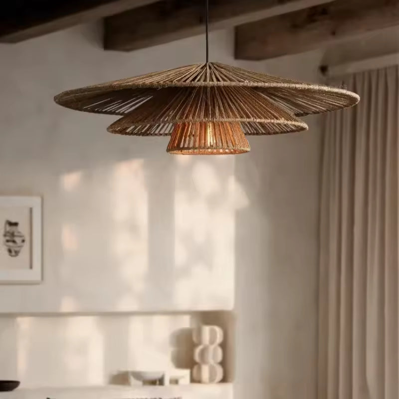 Suspension en rotin à trois abat-jour superposés et ajourés, au design bohème naturel, dans un intérieur chaleureux.