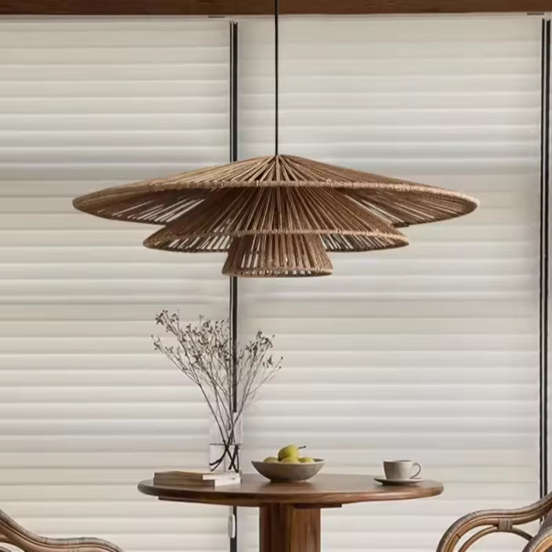 Au-dessus d'une table ronde en bois, lustre en rotin à trois abat-jour ajourés, aux lignes épurées d'inspiration japandi.
