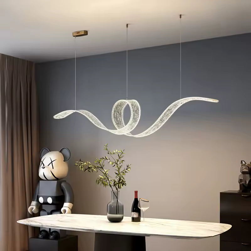 Surplombant une table en marbre, cette suspension LED aux courbes fluides et à boucle centrale évoque un design futuriste.