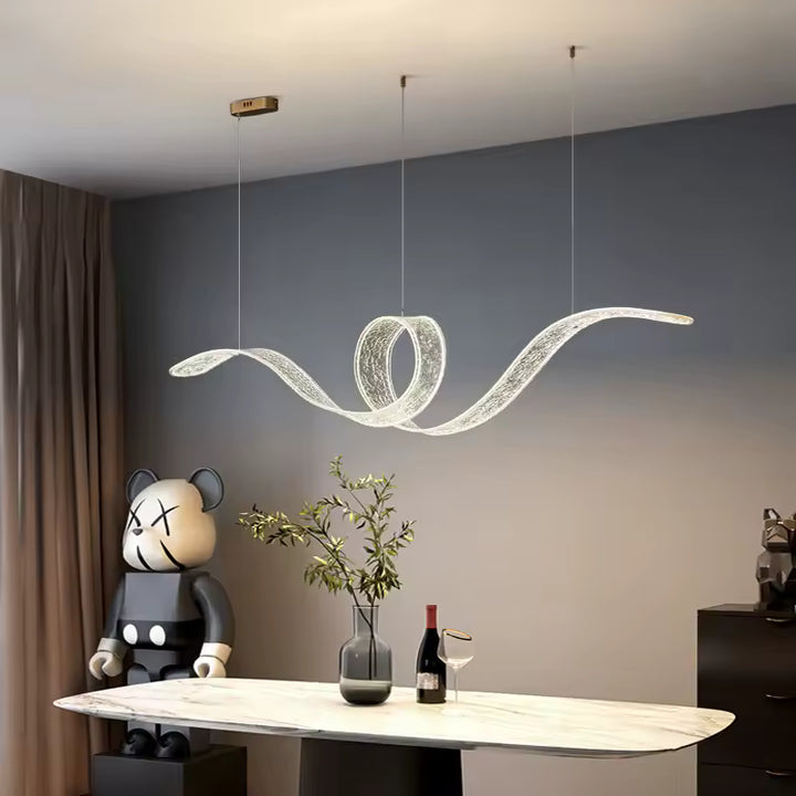 Surplombant une table en marbre, cette suspension LED aux courbes fluides et à boucle centrale évoque un design futuriste.