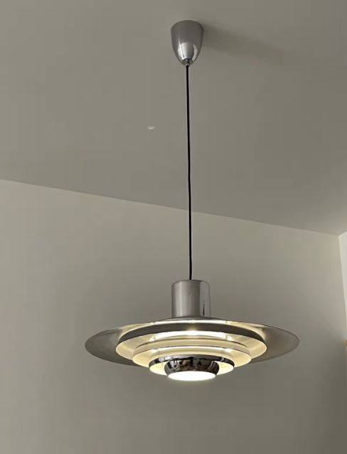 Suspension scandinave vintage chromée à disques étagés, diffusant un éclairage doux au caractère rétro-futuriste.