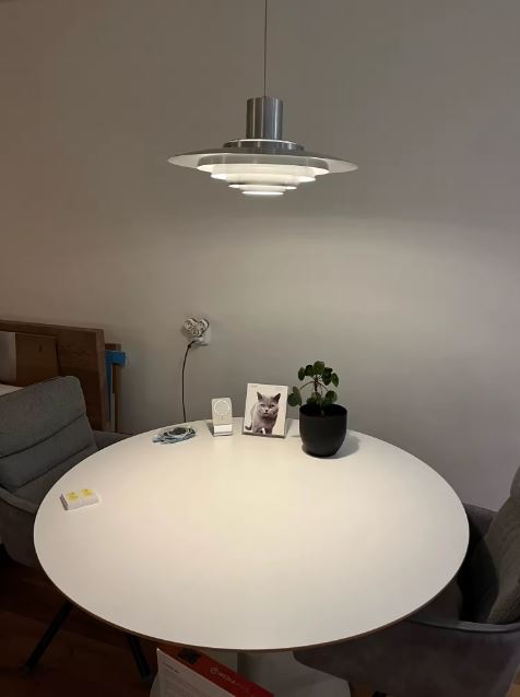 Suspension scandinave vintage en métal chromé à disques superposés, installée au-dessus d'une table ronde.