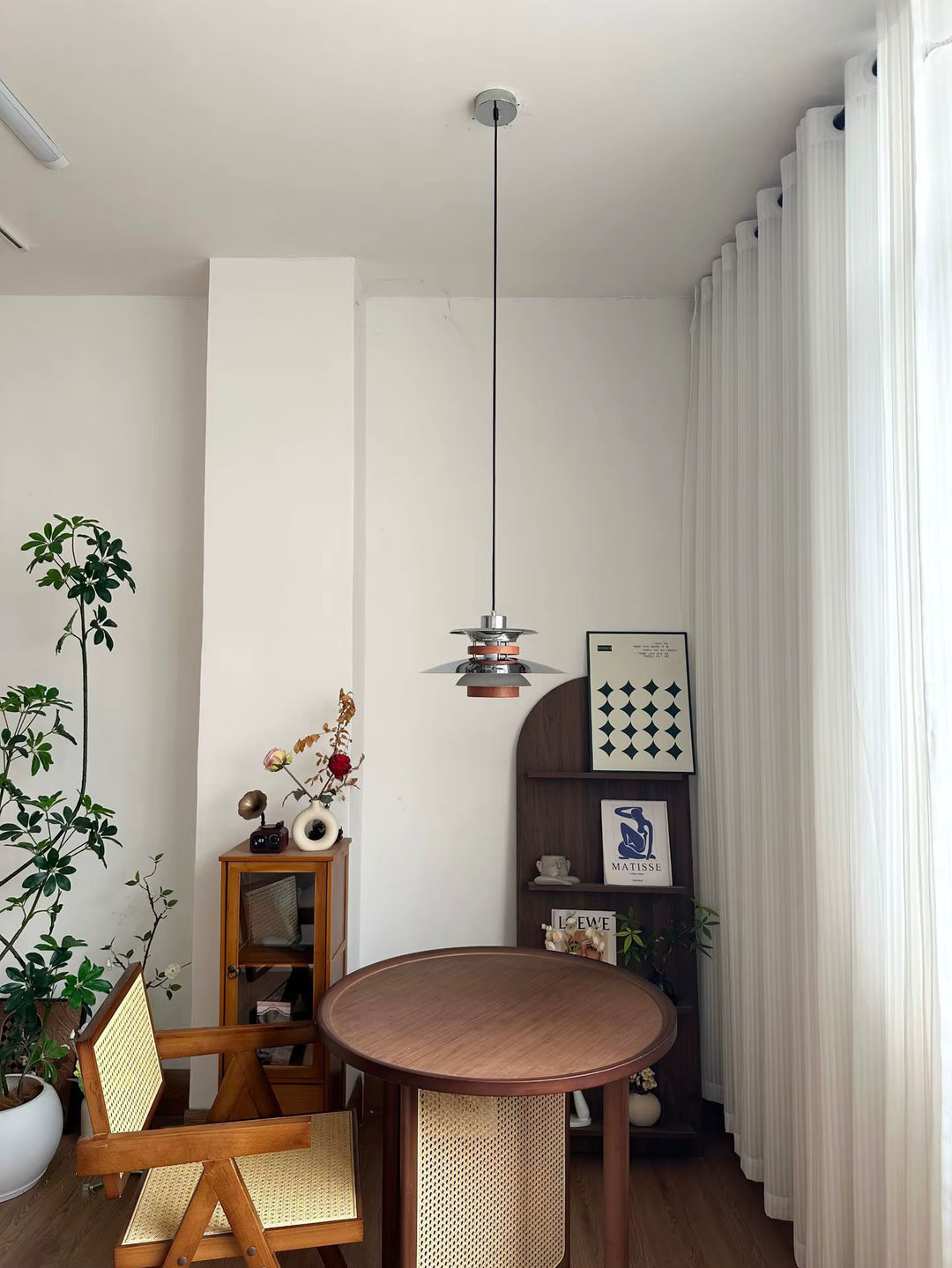 Suspension scandinave vintage en métal chromé et bois, installée au-dessus d’une table dans un intérieur rétro épuré