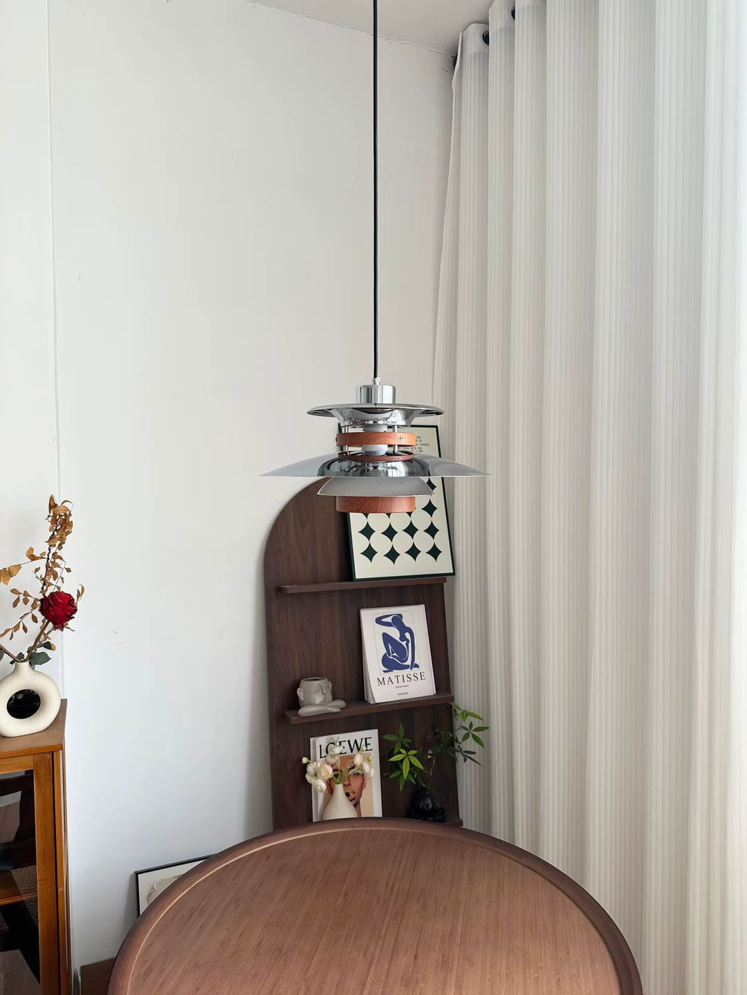 Suspension scandinave vintage en métal chromé et bois au-dessus d’une table ronde, dans un décor rétro épuré
