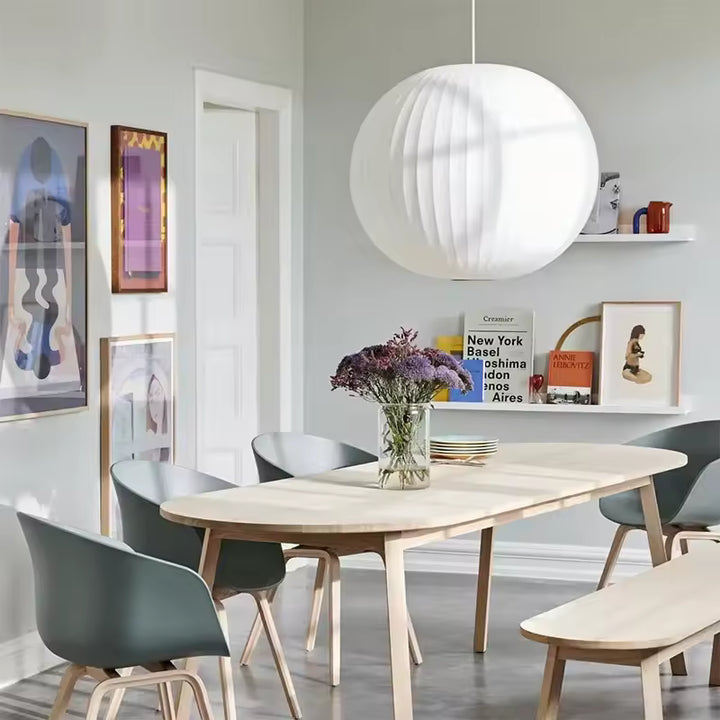 Suspension globe en soie blanche plissée au style scandinave, installée au-dessus d’une table de salle à manger