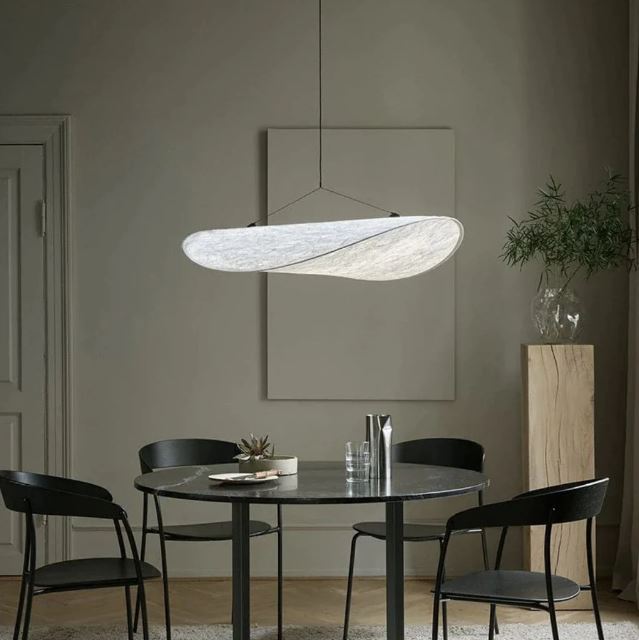 Suspension en soie minimaliste suspendue au-dessus d'une table ronde noire, parfaite pour un intérieur épuré et contemporain.