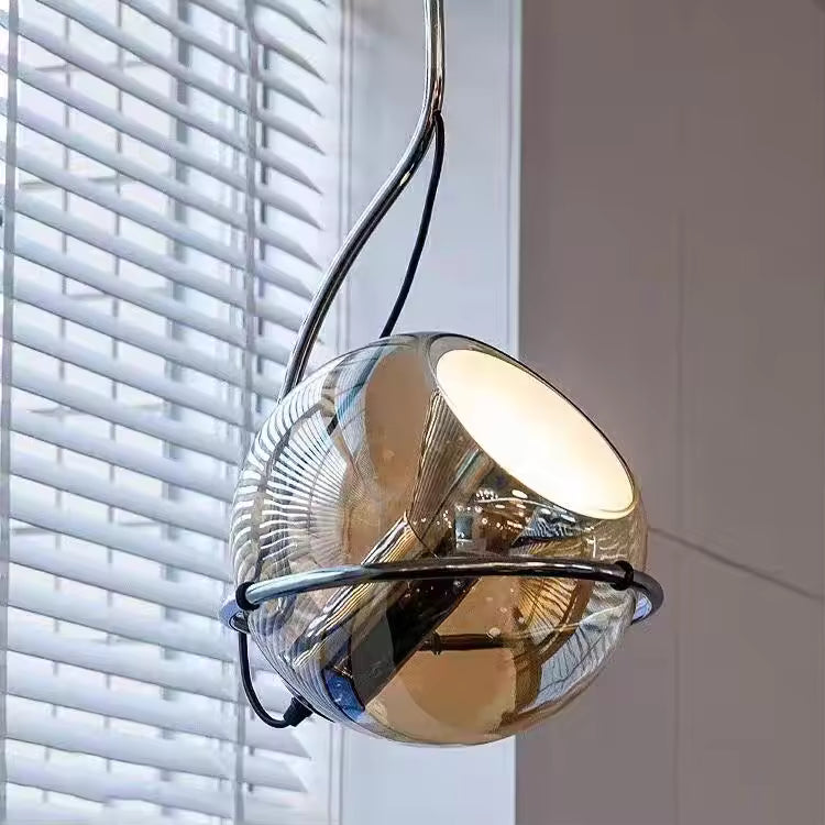 Suspension sphérique en verre ambré cerclée d’un anneau chromé, au design futuriste et contemporain
