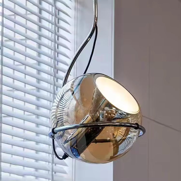 Suspension sphérique en verre ambré cerclée d’un anneau chromé, au design futuriste et contemporain