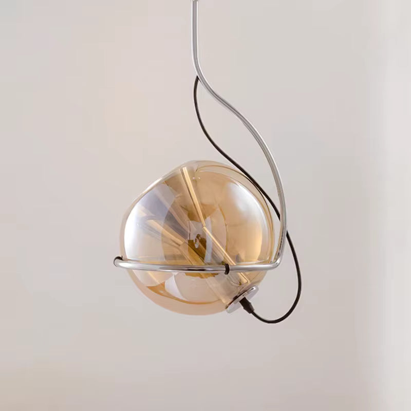 Vue de profil d’une suspension sphérique en verre ambré, soulignée par une structure chromée au design orbital