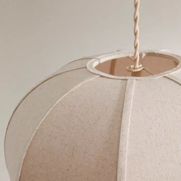 Gros plan sur une suspension en tissu de lin beige, révélant sa texture naturelle et ses pétales galbés